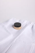 A jar of Fount Society Clay Mask sits on top of a Cozy Earth Waffle Bath Wrap and Waffle Hair Towel on a white background.