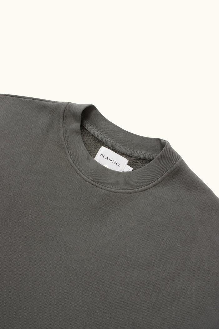 Close-up of a dark gray sweater with a brand label on a white background