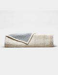 The Cozy Earth Baja Matelasse Coverlet features a neatly folded design with a cream side adorned with subtle lines and a textured gray reverse, shown against a plain white background.|Color:Alabaster/Oceanside