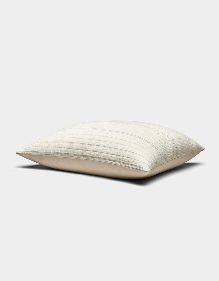 The Baja Matelasse Sham by Cozy Earth is a rectangular, light beige pillow with a subtle striped texture, pictured resting on a flat surface against a plain white background.|Color:Alabaster/Oceanside