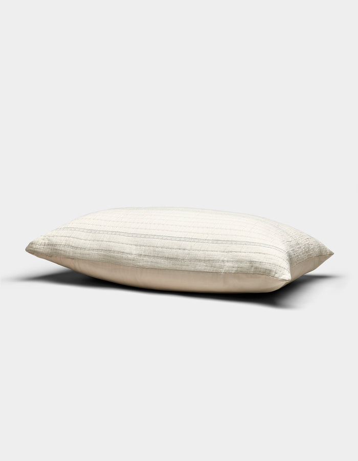 The Baja Matelasse Sham by Cozy Earth, in a cream shade with subtle horizontal stripes, rests on a plain light gray background. Its soft, gently flattened appearance suggests both comfort and support.|Color:Alabaster/Oceanside