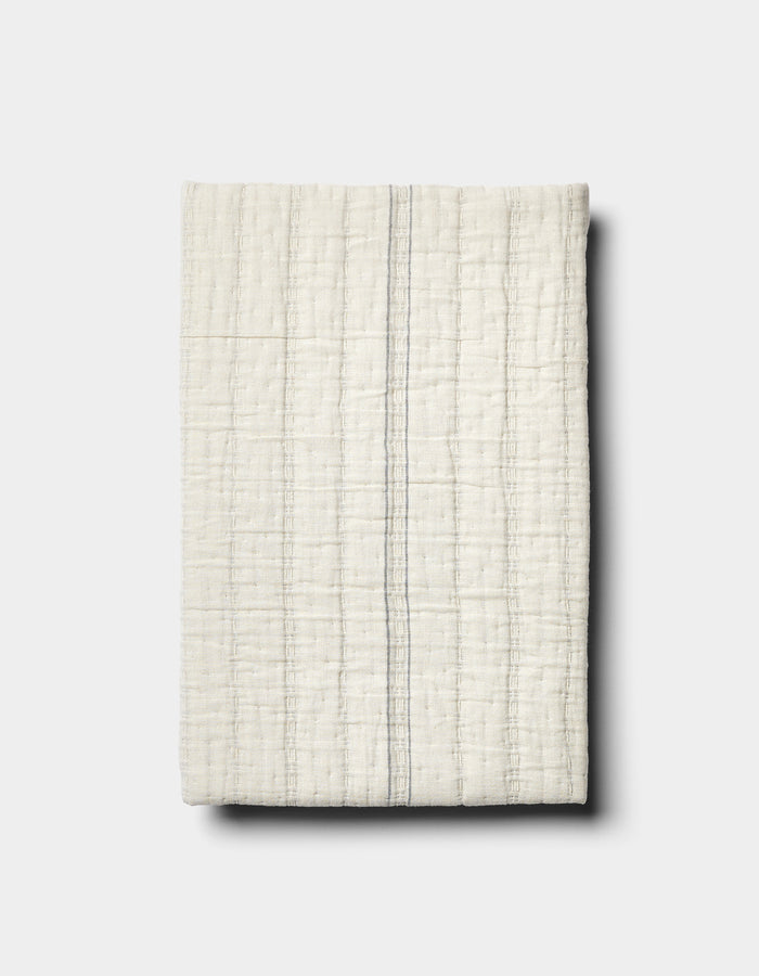 The Baja Matelasse Sham by Cozy Earth features off-white textured fabric with a subtle grid pattern and a single thin grey vertical stripe, displayed on a light grey background.|Color:Alabaster/Oceanside