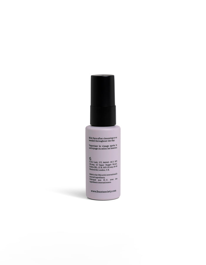 A small, white spray bottle facing backwards with a black cap and circular logo stands upright on a white background. |Size:Mini