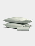 The Cozy Earth Bamboo Bedding Basic Bundle features two light gray pillows stacked together with a matching pillowcase rolled in front, all displayed against a plain white background.|Color:Laurel