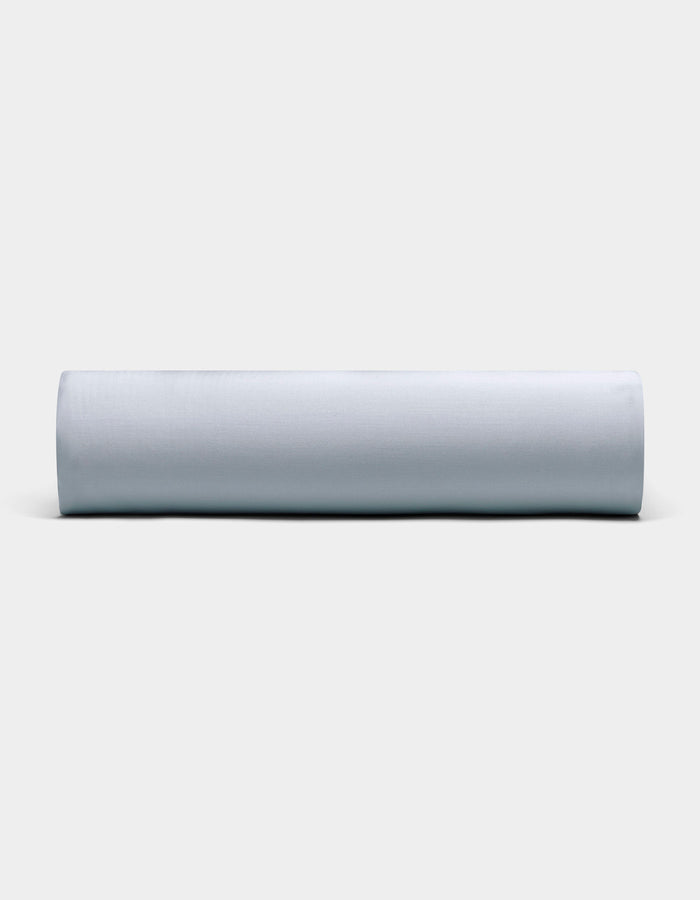 A Bamboo Fitted Sheet by Cozy Earth, neatly rolled and displayed horizontally, is showcased against a plain, light background with its soft light gray fabric visible from the front.|Color:Shore