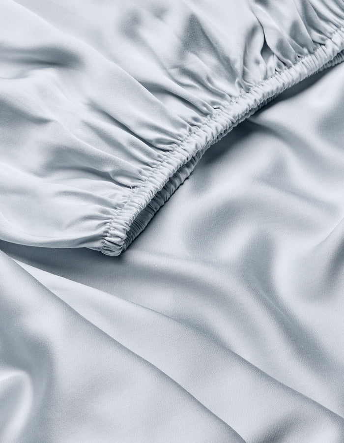 Close-up of Cozy Earth Bamboo Fitted Sheet in light blue, featuring gathered, ruched stitching on one edge for soft folds and a smooth, silky sheen.|Color:Shore