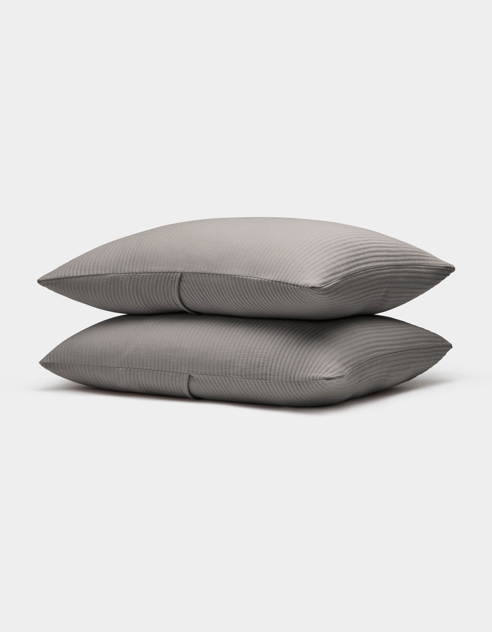 Two neatly stacked Bamboo Coverlet Shams by Cozy Earth in gray with stripes, displayed on a plain white background.|Color:Charcoal
