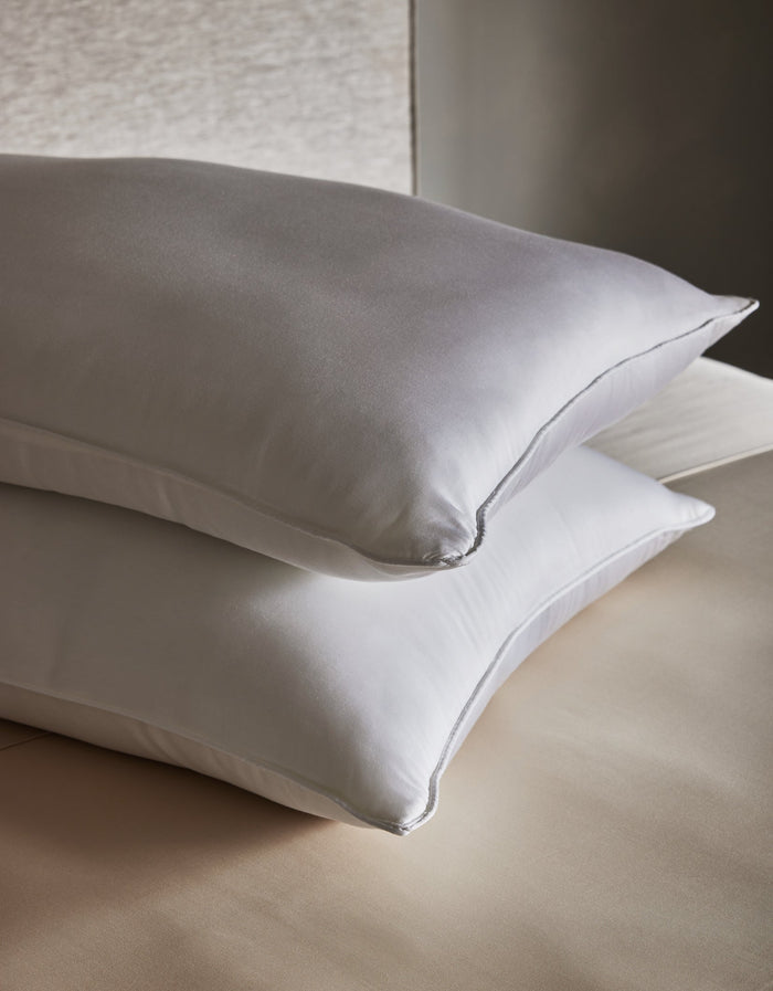 Two Cozy Earth Bamboo Down Alternative Pillows are neatly stacked on a beige bed with smooth, clean sheets, set against a neutral background.Standard King