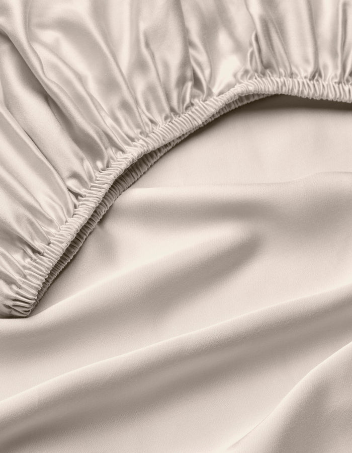 A close-up of the Cozy Earth Bamboo Fitted Sheet in light beige, highlighting its silky, smooth fabric, gathered elastic edges, and soft folds.|Color:Driftwood
