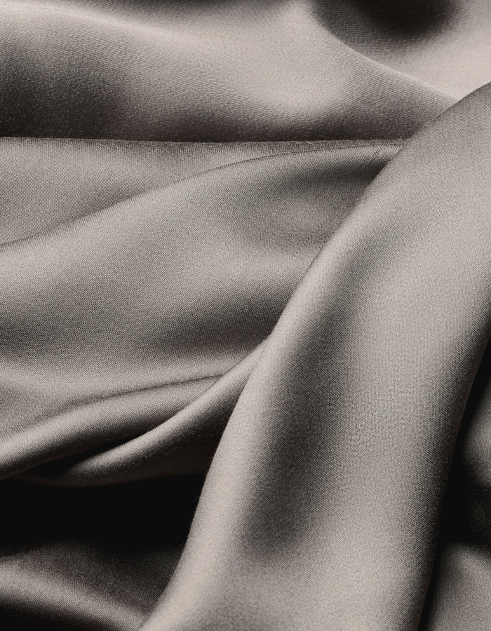 The Cozy Earth Bamboo Flat Sheet features smooth, folded silver-gray satin fabric with a soft sheen, offering an elegant, flowing texture and subtle highlights and shadows across the surface.|Color:Charcoal