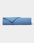 A neatly folded Bamboo Jersey Sheet Set by Cozy Earth in blue rests on a plain white surface, with one corner flipped to display the soft fabric texture.|Color:Sailor