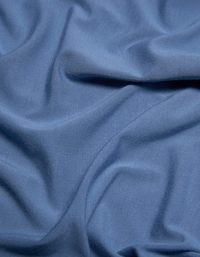 A close-up of Cozy Earth’s Bamboo Jersey Sheet Set in light blue, highlighting the gentle folds, soft creases, and subtle textured pattern on its surface.|Color:Sailor