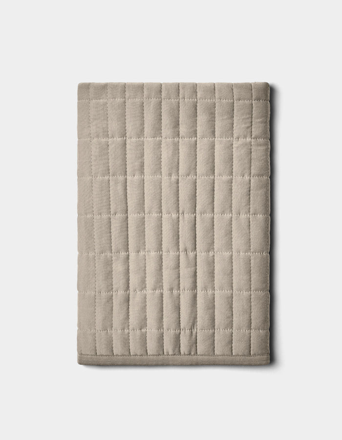 The Bamboo Jersey Quilted Shams by Cozy Earth, shown neatly folded in beige with a grid pattern, are displayed on a plain light background.|Color:Driftwood