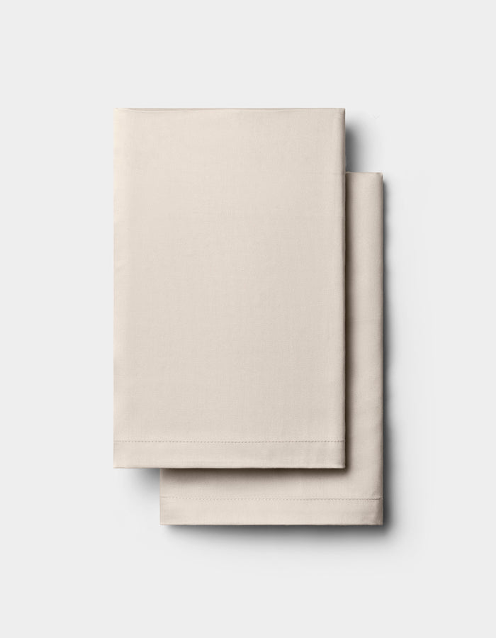 Two neatly folded, light beige Cozy Earth Bamboo Pillowcases are stacked on a plain white background.|Color:Driftwood