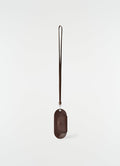 Glasses case in glossy dark brown vegetable-tanned leather with strap by LEMAIRE on plain white background