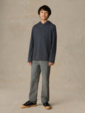 Child wearing a navy hoodie and grey pants against a beige background