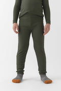 A child wears Cozy Earth’s Children’s Bamboo Waffle Knit Base Layer Pant in Olive, paired with a matching long-sleeve top and gray socks with orange toes, standing against a plain white background. The child’s face is not shown.|Color:Olive