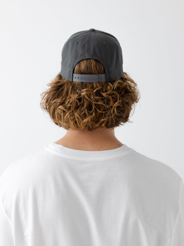 A man wearing a grey cap facing backwards on a white background |Color:Charcoal/Black