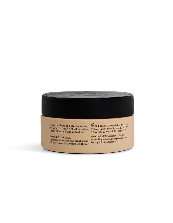 A beige jar labeled "Clay Mask" by Cozy Earth, with a black lid, is shown from the side. Black text on the jar displays product instructions and info, highlighting its use as a skincare item.