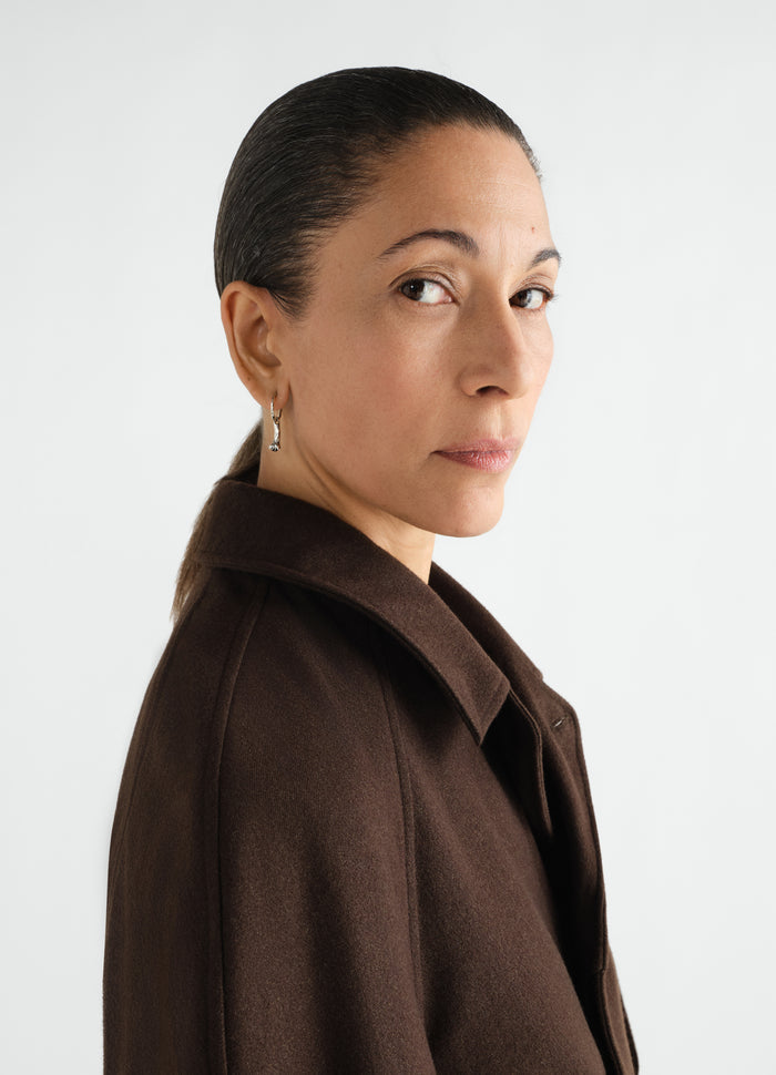 Clove silver earrings from LEMAIRE worn by model with dark brown wool coat side view
