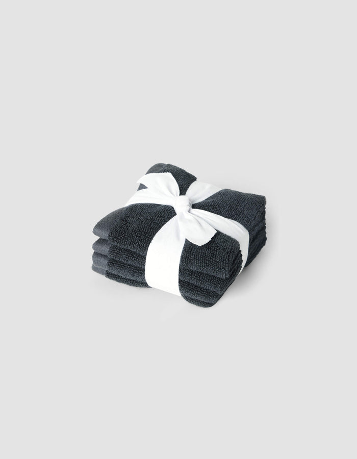 A neatly folded stack of Cozy Earth Complete Cleansing Cloths in dark gray, tied with a white ribbon, set against a plain light gray background.|Color:Graphite