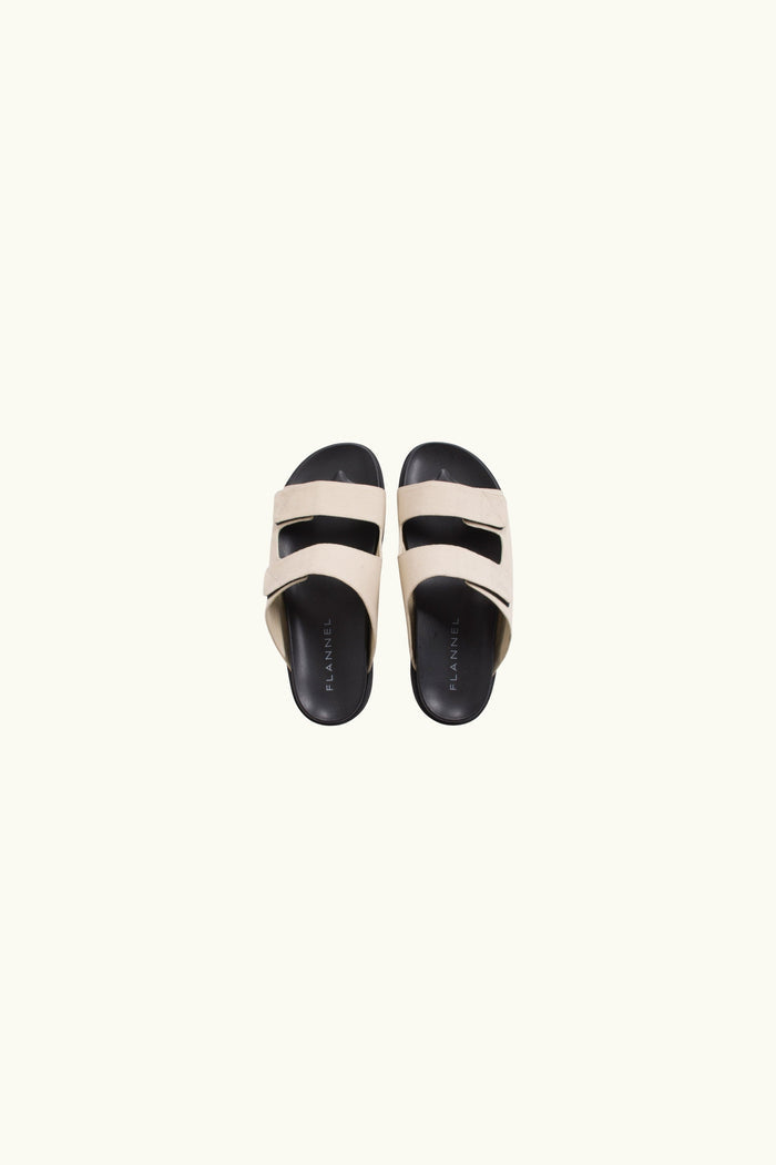 Pair of white canvas and black rubber sandals on a white background