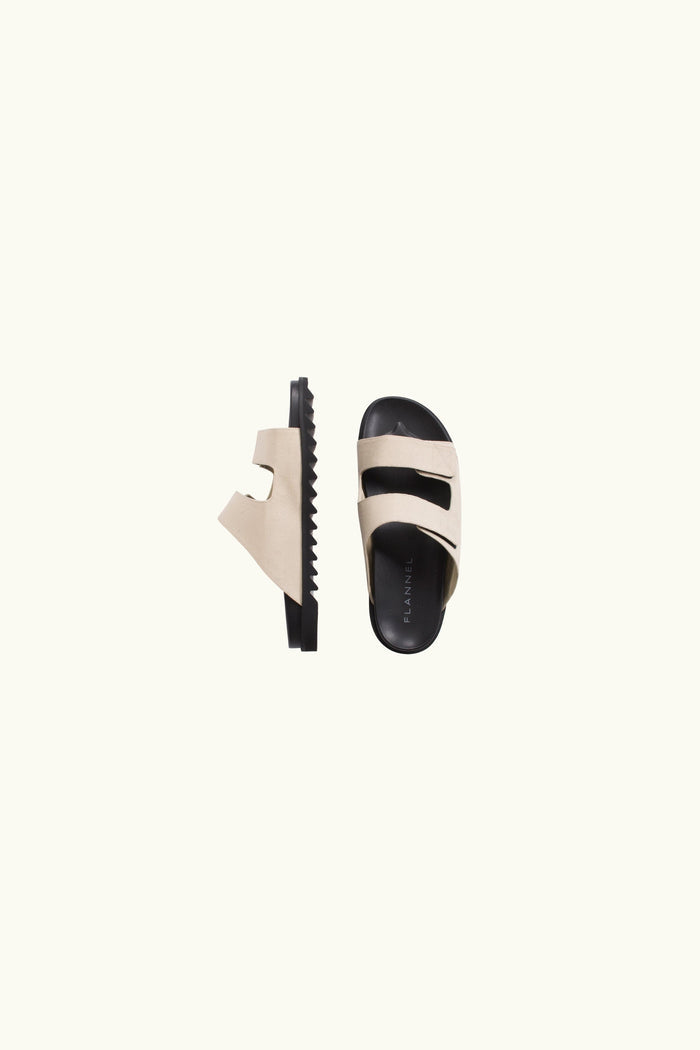 Pair of natural canvas and black rubber sole slides on a white background