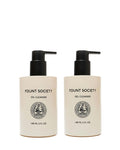 Two beige pump bottles from Cozy Earth’s Double Cleanse Duo—Oil Cleanser on the left, Gel Cleanser on the right—feature black pumps, black text, round front emblems, and each holds 148 mL (5 fl oz).