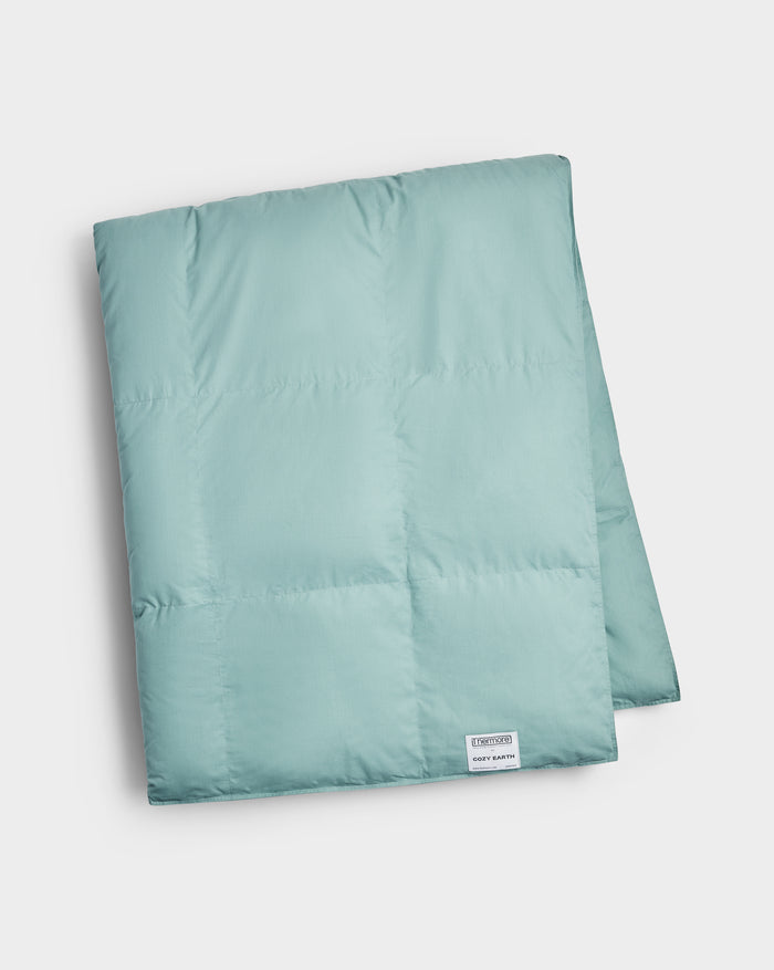 A neatly folded light teal Down Alternative Throw by Cozy Earth, featuring a small white label in the corner. The blanket looks soft and plush, displayed against a plain white background.|Color:Pond