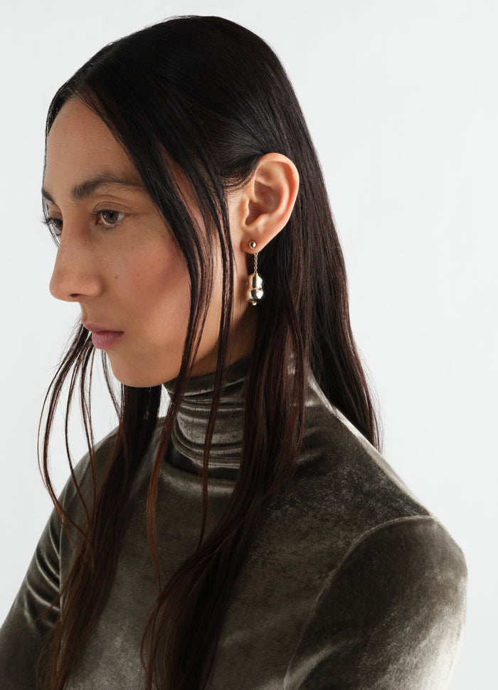 Blown glass silver earring worn by model with brown velvet turtleneck LEMAIRE side view close-up