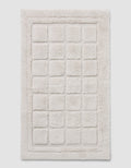 The Cozy Earth Grid Bath Mat is a rectangular, off-white mat with a raised grid design and a thick, fluffy border.|Color:Light Grey