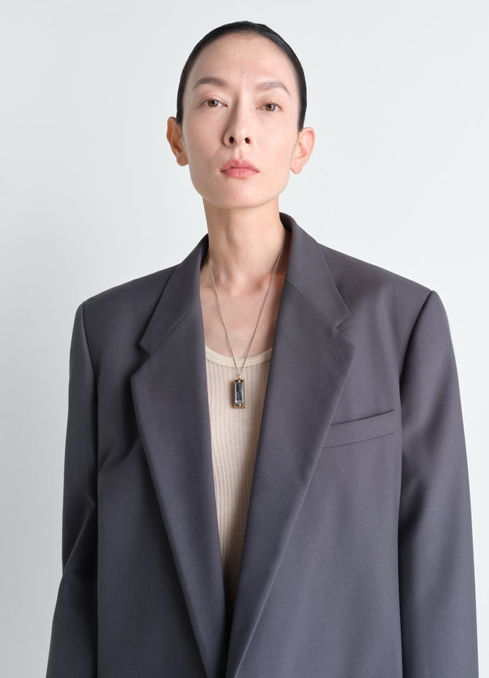 Harmonica silver-tone metal necklace worn by model LEMAIRE close-up front shot with grey blazer and beige top