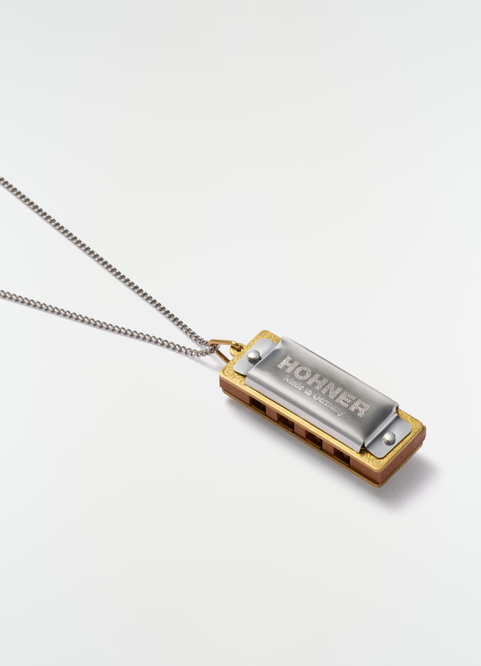 Harmonica necklace with silver chain and metal harmonica pendant, LEMAIRE, styled on white background