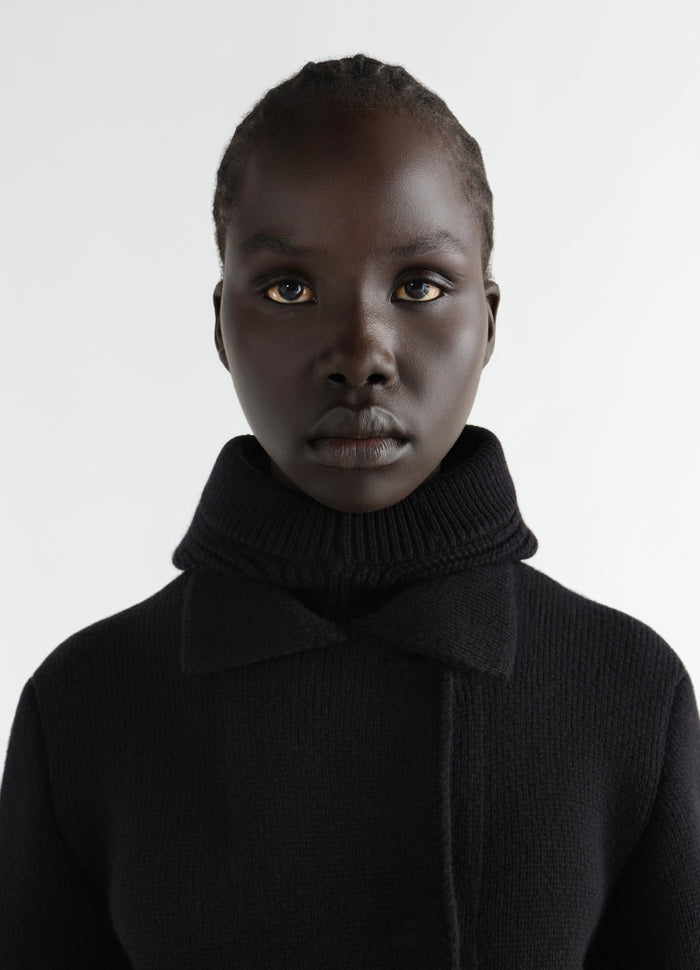 Balaclava in black worsted wool by LEMAIRE worn by model close-up with turtleneck collar visible
