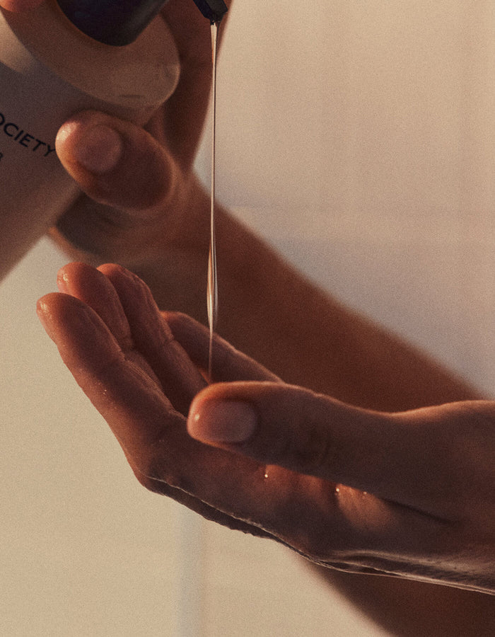 A close-up of hands pouring Cozy Earth's Fount Society Intro Kit into their palm, softly illuminated by warm light.