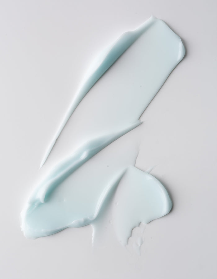 The Water Cream Moisturizer by Cozy Earth is gently applied across a smooth, white surface. Its texture is glossy and soft, with broad sweeping strokes creating a slightly abstract pattern. |Size:Mini
