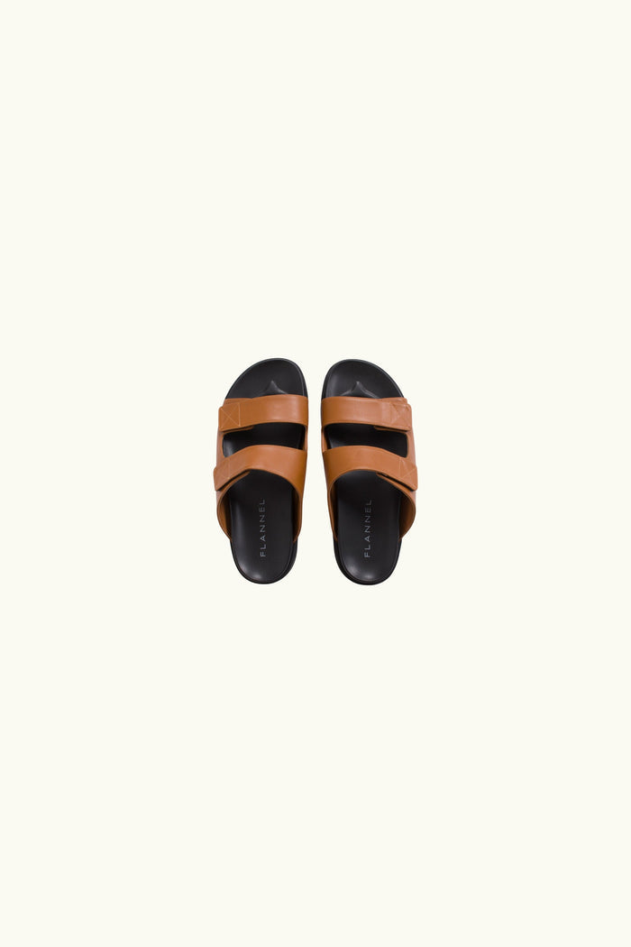 Pair of brown and black leather sandals on a white background