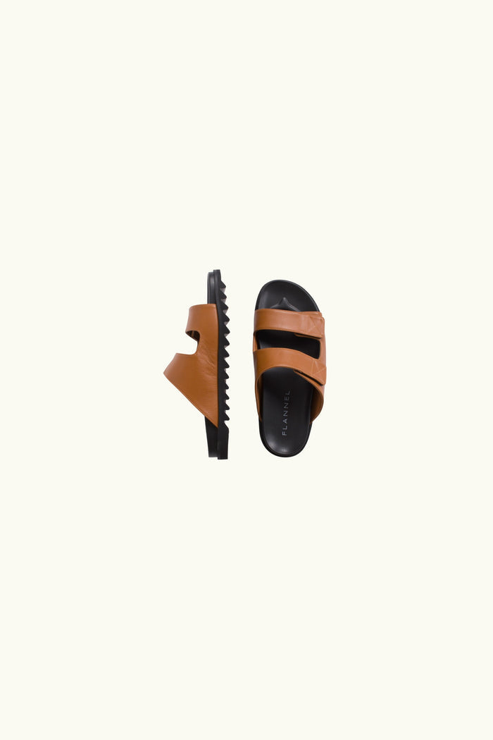 Pair of brown sandals with black soles on a white background