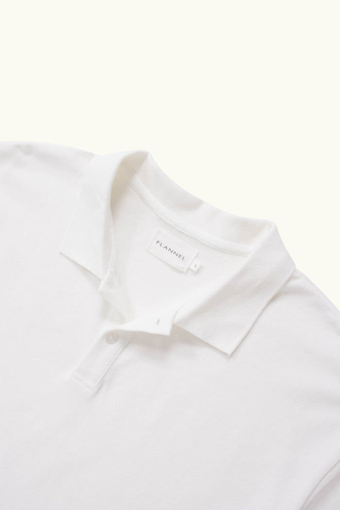 Close-up of a white cotton polo shirt on a white background