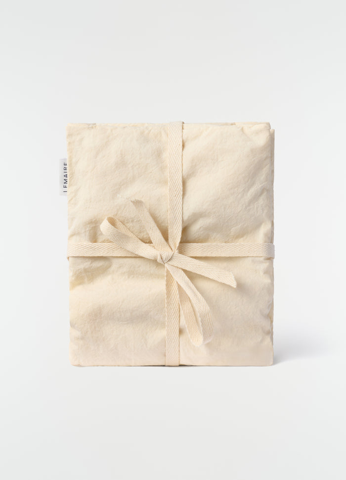 Lavender cushion in beige cotton with ribbon tie detail by LEMAIRE front view on plain white background