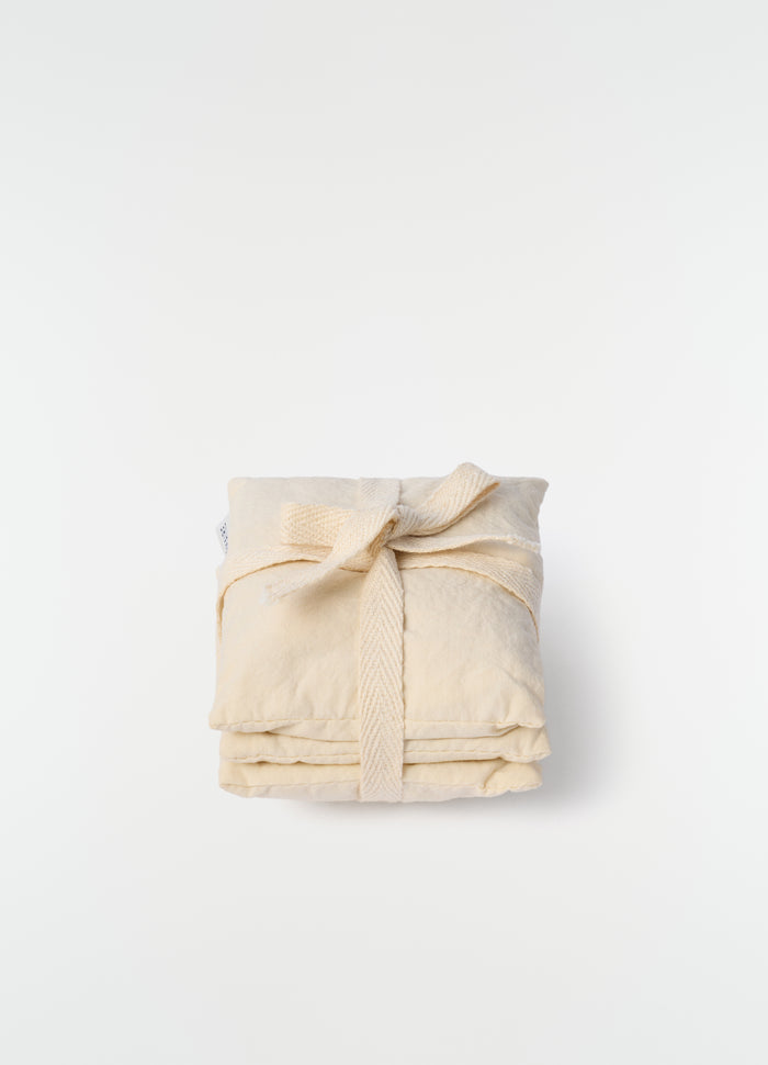 Lavender cushion XS in beige cotton with tied strap detail by LEMAIRE on plain white background