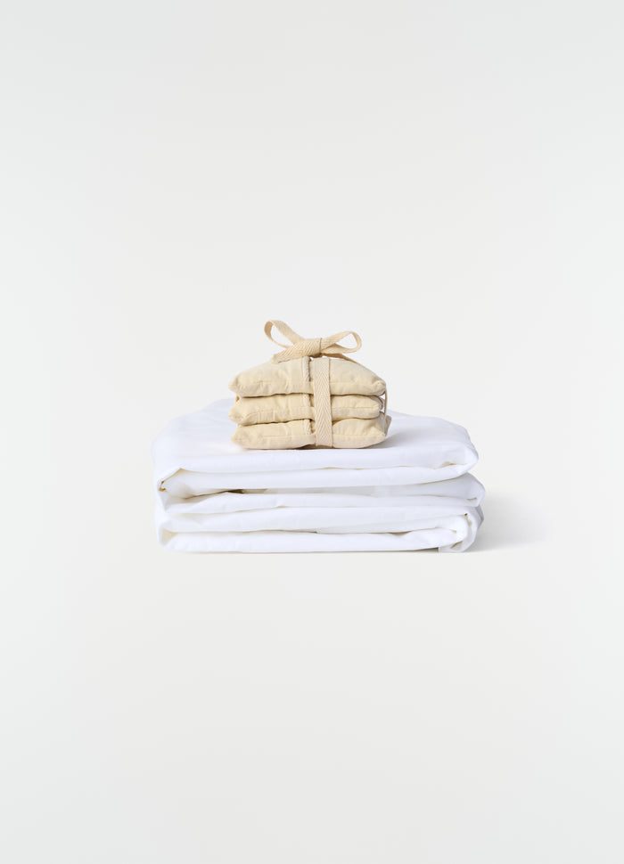 Lavender Cushion XS in beige cotton with strap detail by LEMAIRE styled on folded white fabric background