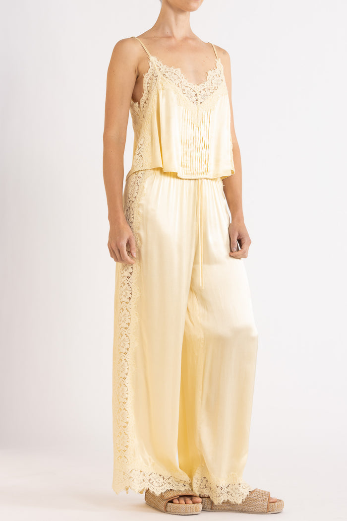 Woman wearing matching vanilla lace-trimmed camisole and pant.