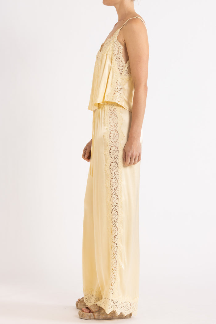Woman wearing matching vanilla lace-trimmed camisole and pant.