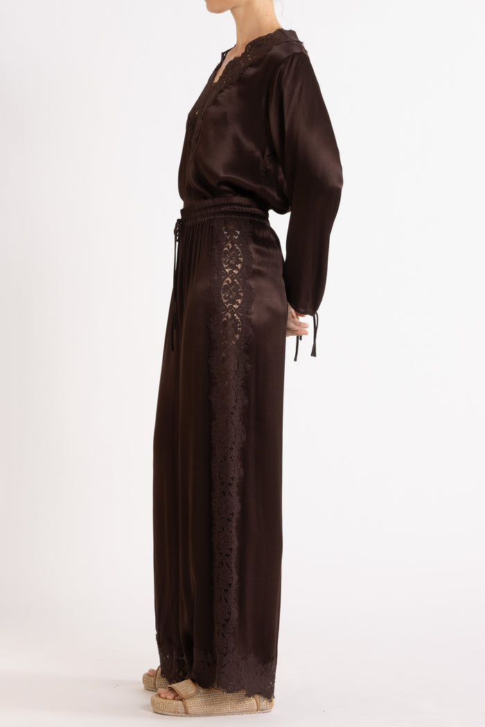 Woman wearing a brown long sleeve top and pant with lace details on a white background