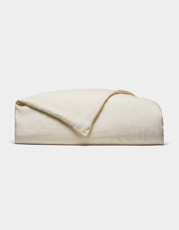 The Cozy Earth Linen Duvet Cover, in an off-white shade, is neatly folded against a white background. Its soft, slightly textured fabric is visible with one corner casually turned over.|Color:Flax