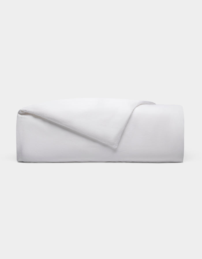 The Cozy Earth Linen Duvet Cover, neatly folded with one corner turned down, is displayed against a plain light gray background.|Color:White
