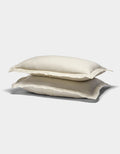 Two cream-colored Cozy Earth Linen Shams with slightly ruffled edges are stacked on top of each other against a plain white background.|Color:Flax