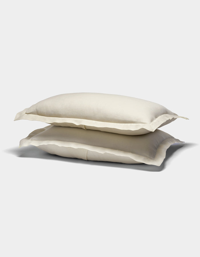 Two cream-colored Cozy Earth Linen Shams with slightly ruffled edges are stacked on top of each other against a plain white background.|Color:Flax