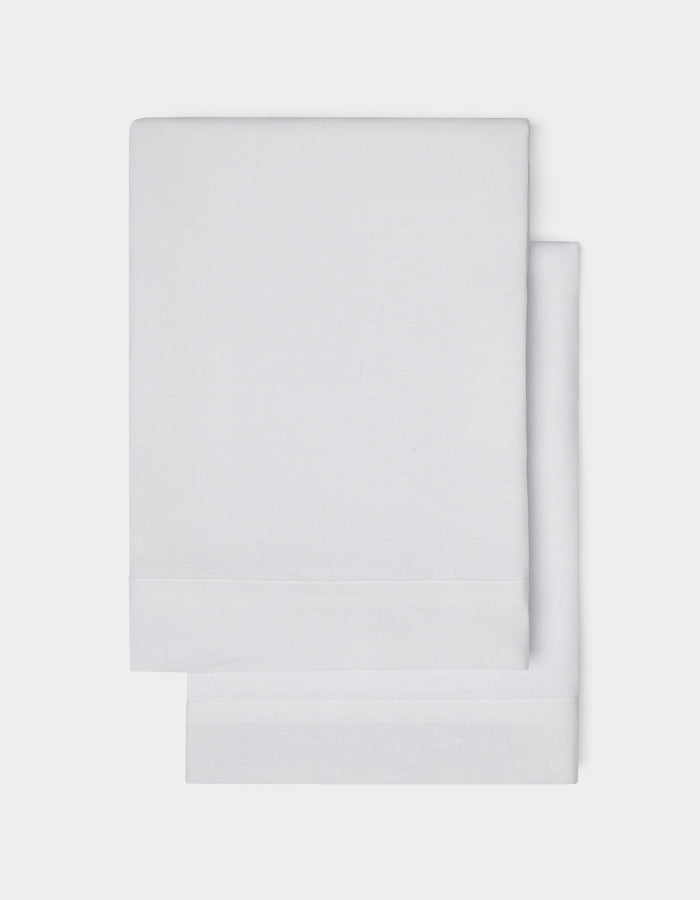 Cozy Earth Linen Shams, neatly folded in plain white with a simple hemmed edge, are shown on a white background.|Color:White